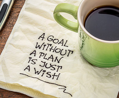 Picture of a coffee cup on a napkin which has: A goal without a plan is just a wish written on it